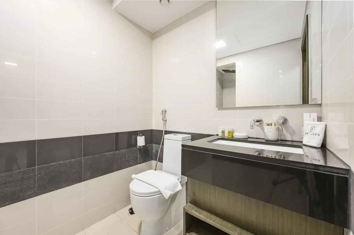 Un baño con azulejos, un inodoro junto a un lavabo y un espejo.