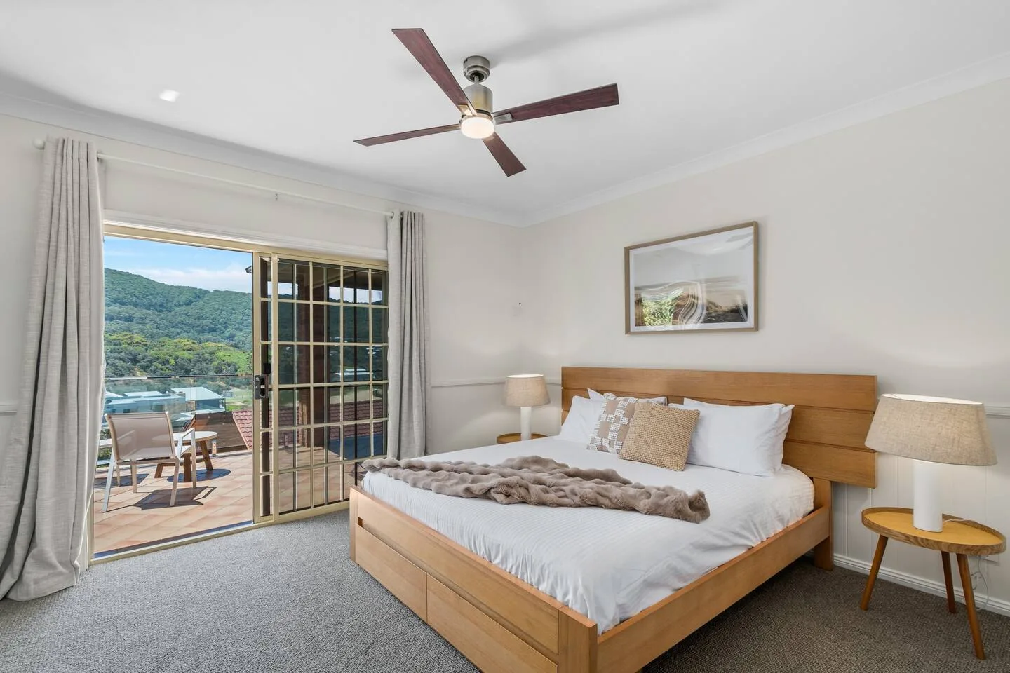 A bedroom with a bed beside sliding glass doors opening onto a balcony.