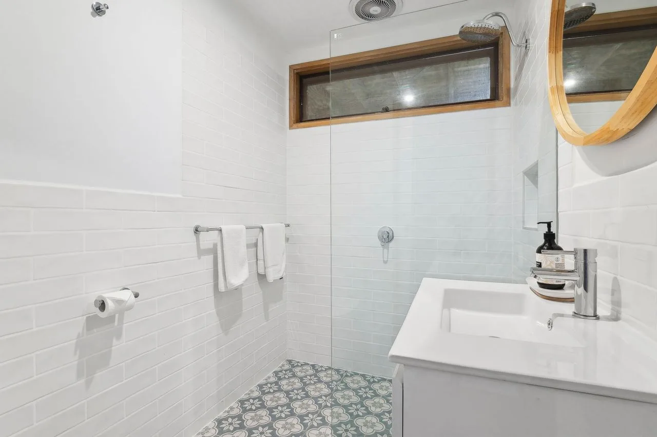 A tiled bathroom with a sink and shower area.