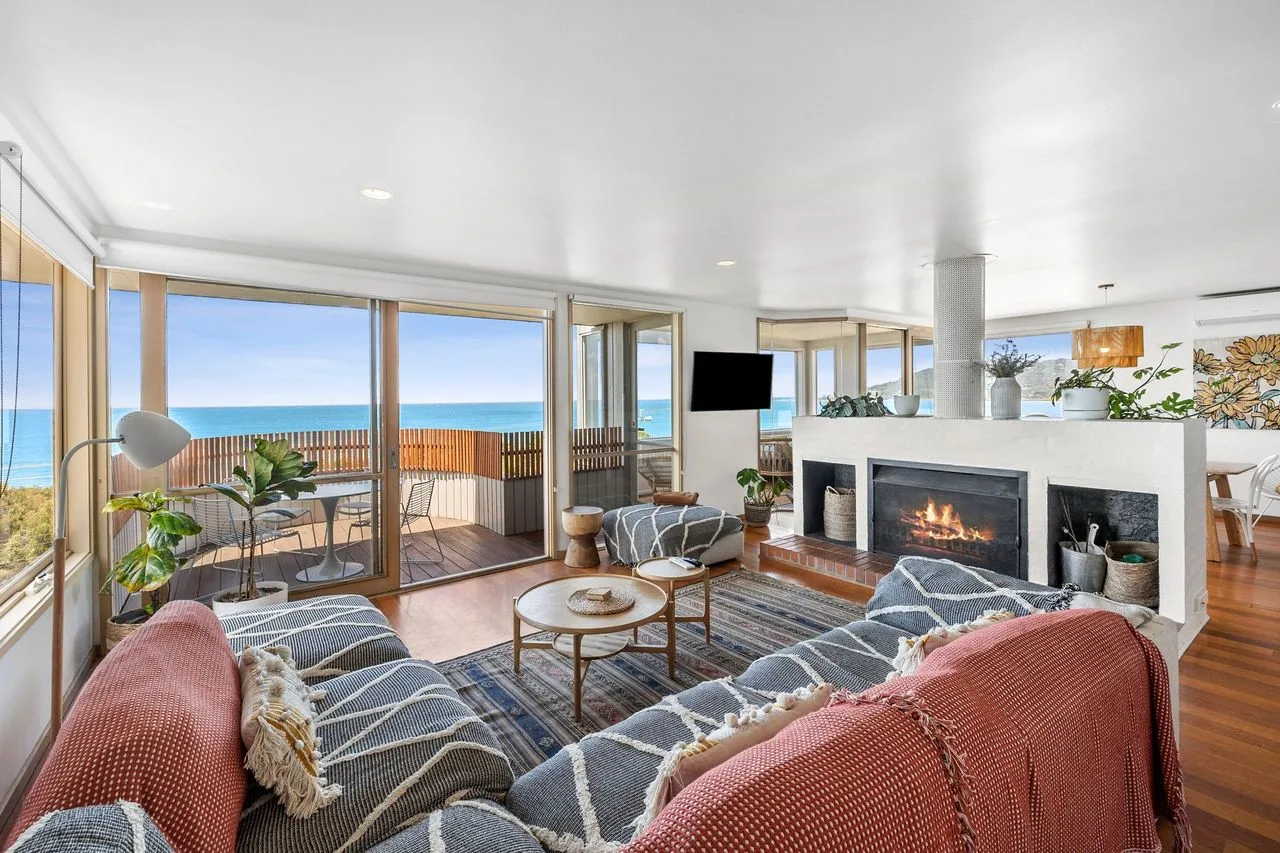A living room opens onto a balcony with ocean views.