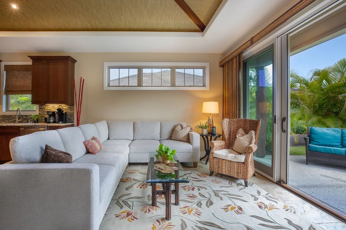 A bright living room with sectional seating, a glass coffee table, and sliding doors opening to a patio.