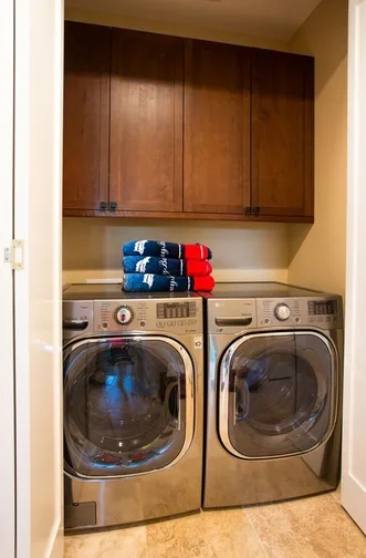 A laundry area with front-loading washer and dryer beneath wooden cabinets.