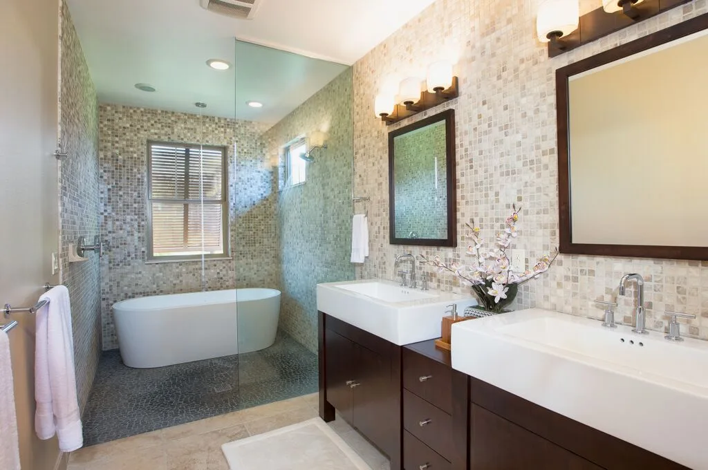 A tiled bathroom with a bathtub, glass shower, and two sinks.