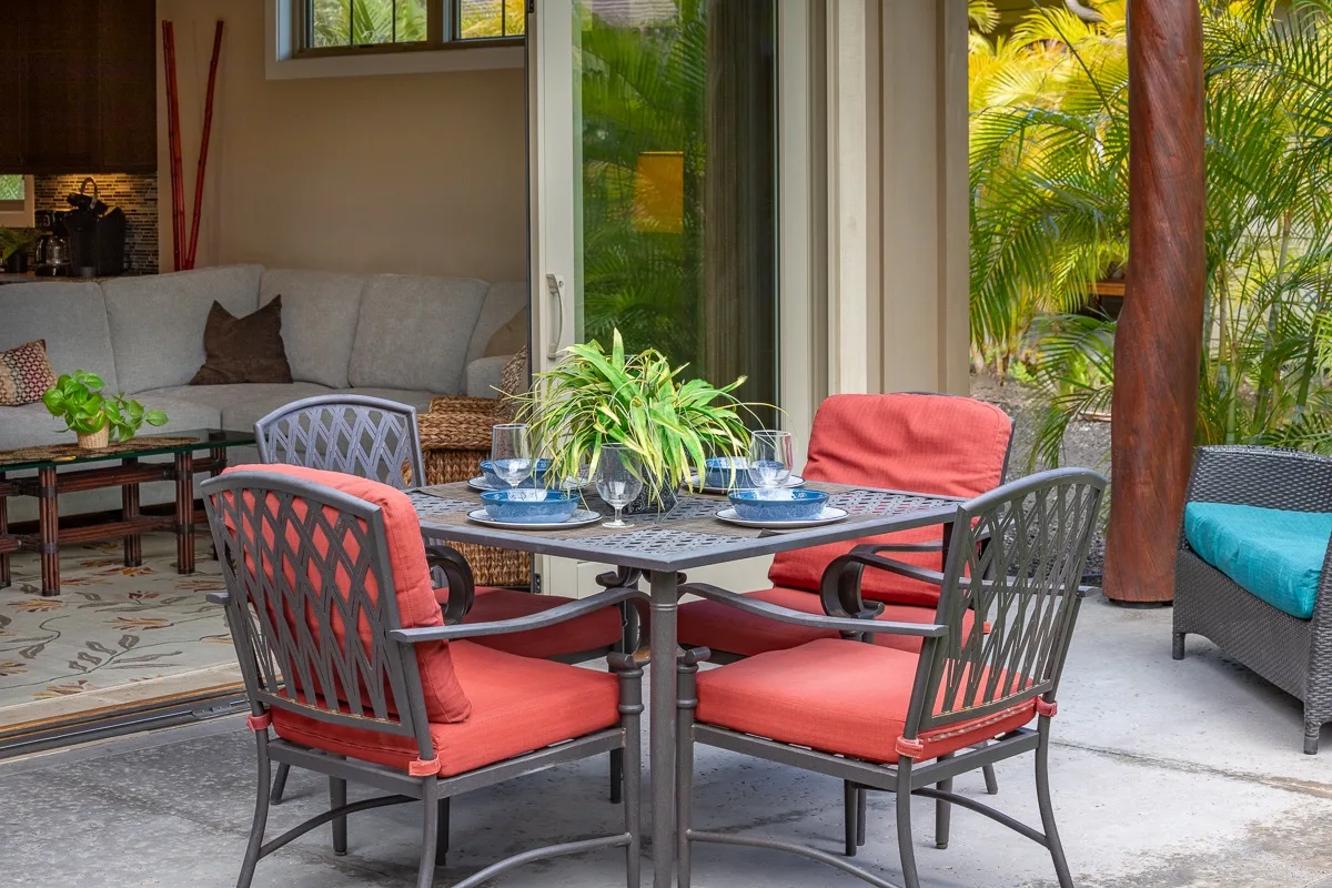 A patio dining area with a table and cushioned seating beside a glass door.