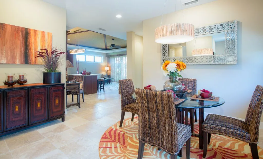 A dining area with woven seating around a glass table and a colorful floral centerpiece.