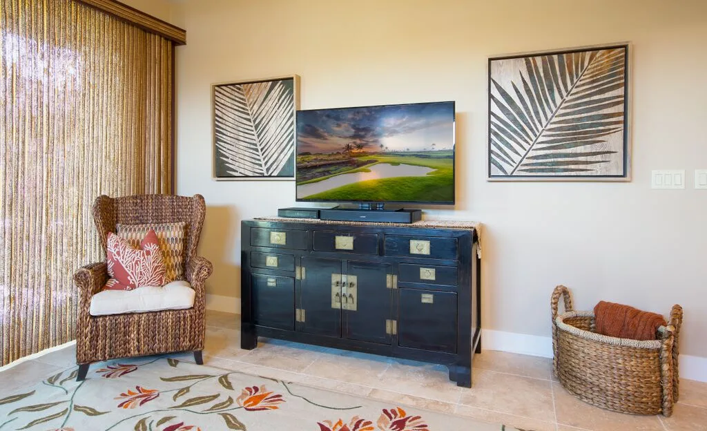 A living room with a television on a dark cabinet and woven seating.