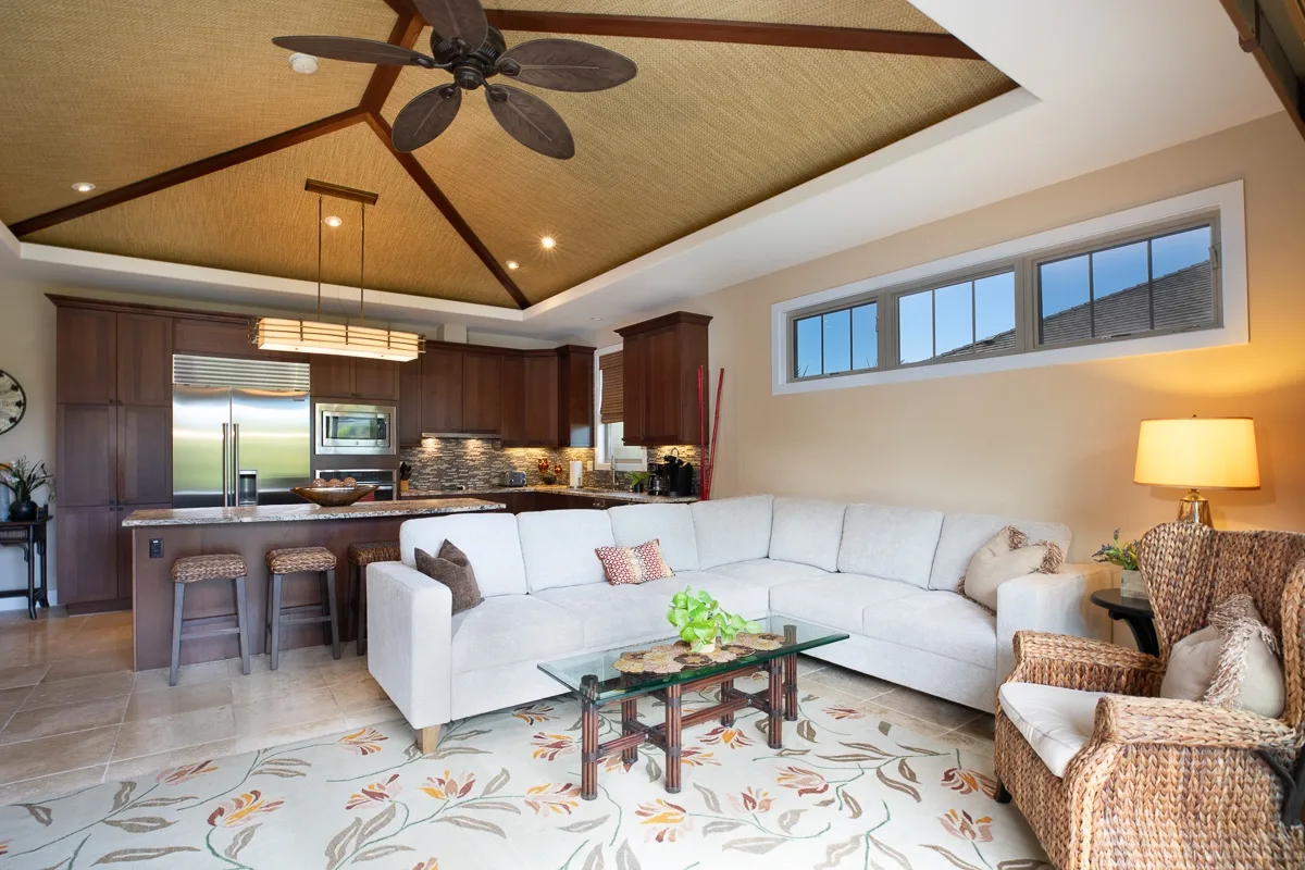 A living room with a white sectional seating area beside an open kitchen.