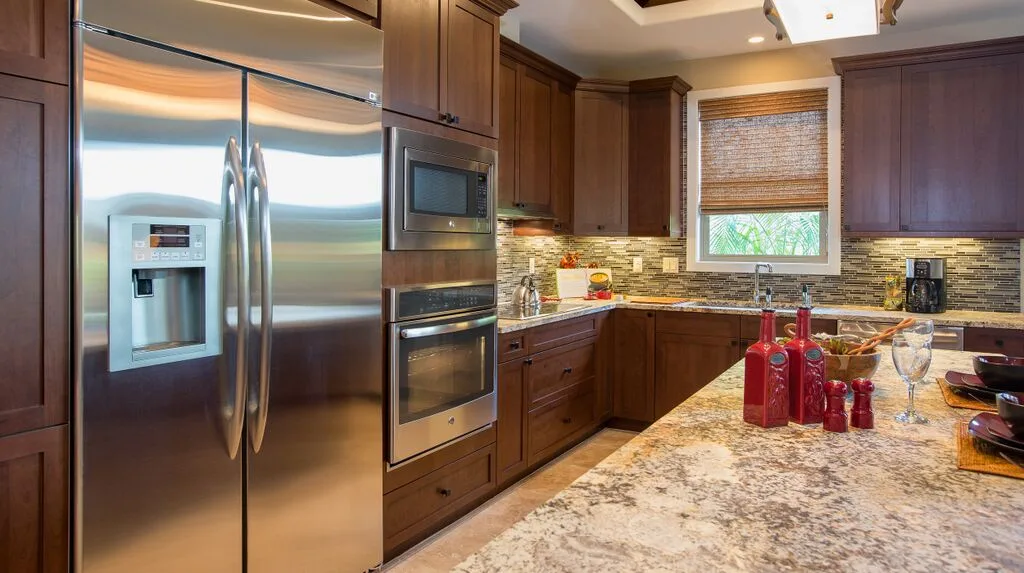 A spacious kitchen with dark wood cabinets, stainless steel appliances, and a stone countertop.