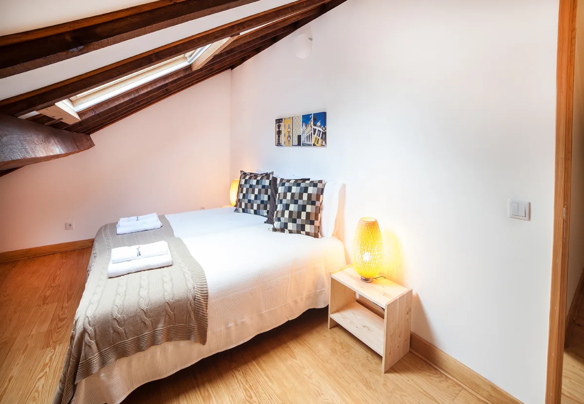 A bedroom with a double bed, folded towels, and a small bedside table.