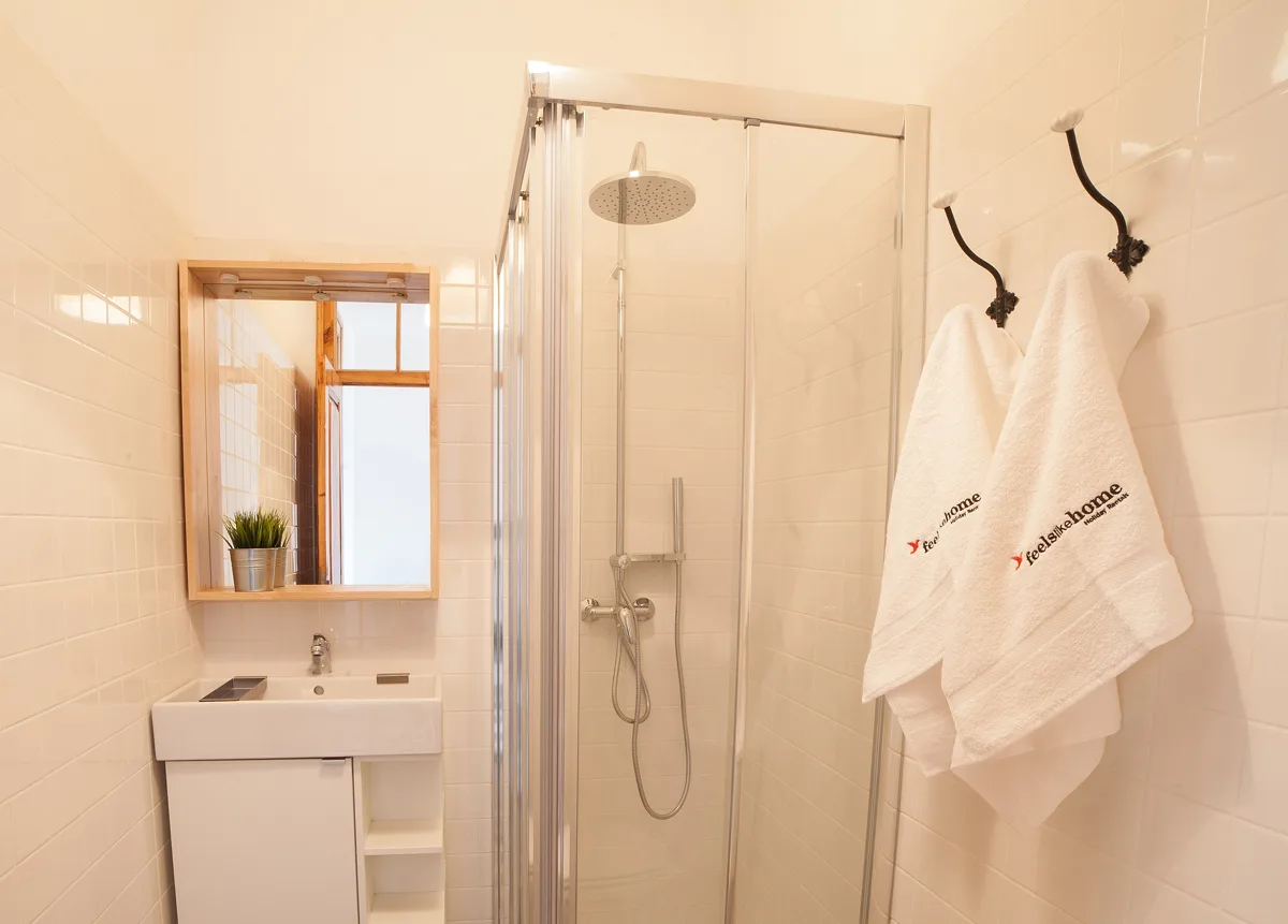 A tiled bathroom with a glass shower and a sink.