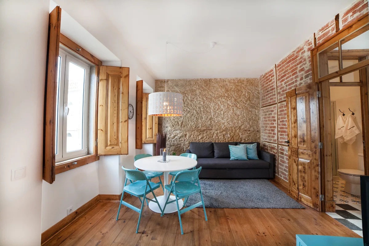 A living room with a dining table, seating, and exposed brick walls.