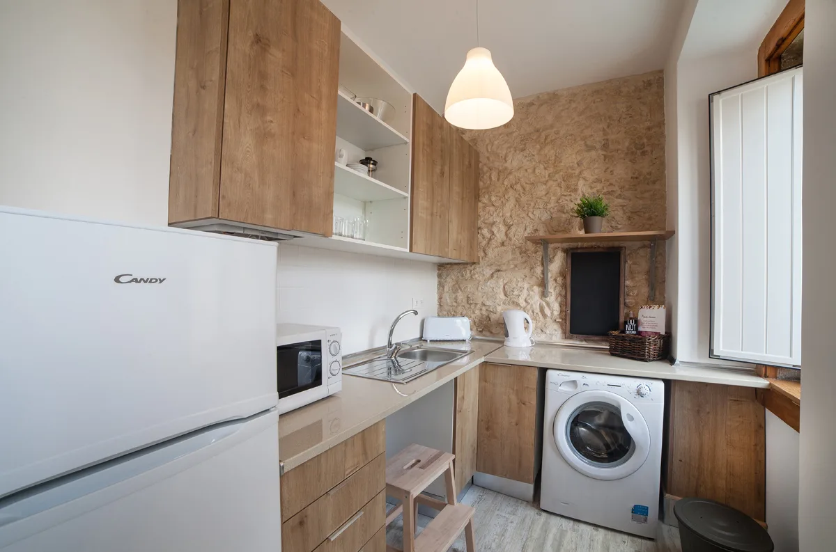 A compact kitchen with wood cabinetry, a sink, and a washing machine.