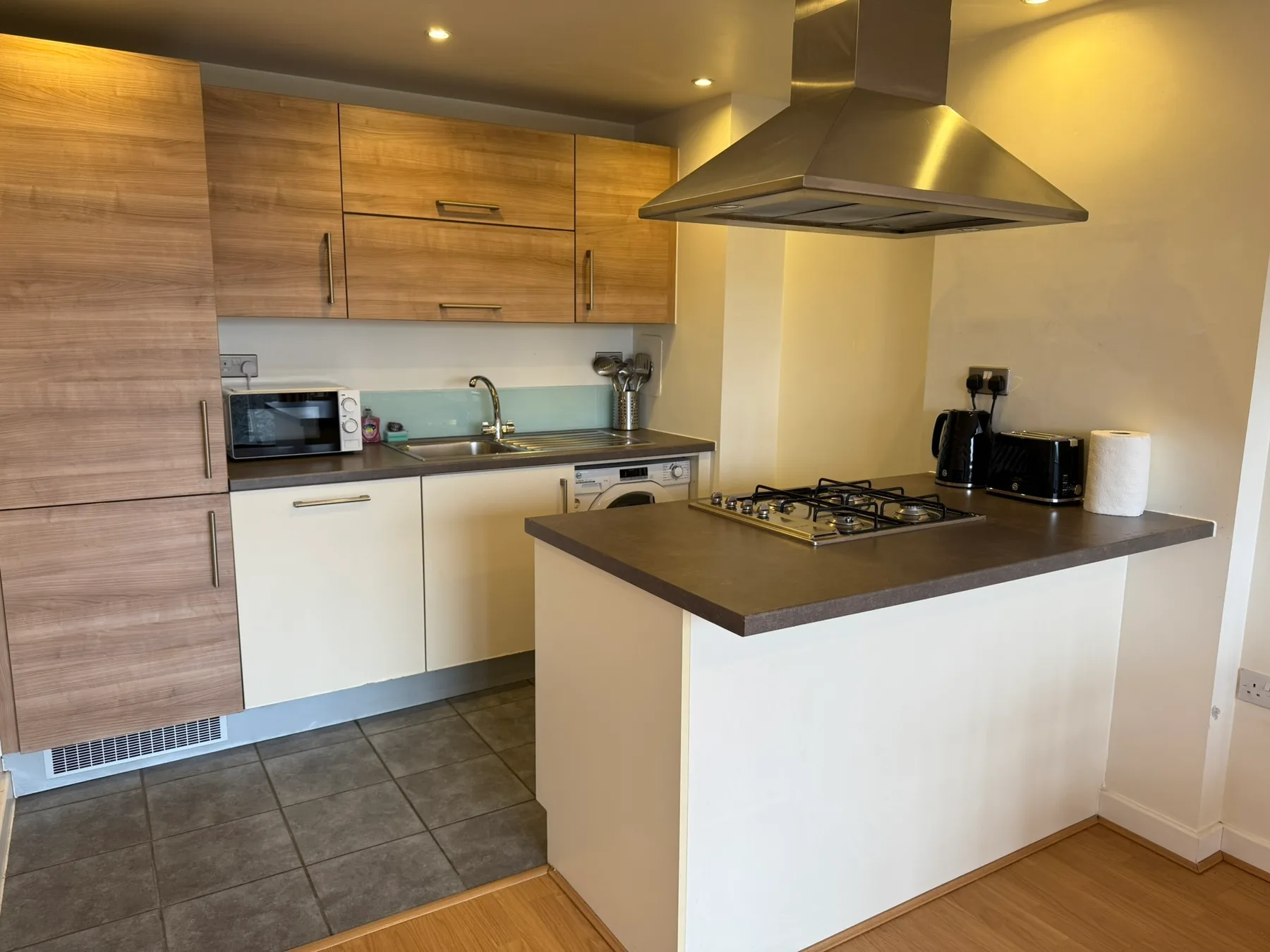 A modern kitchen with wood cabinets and a central cooking island.