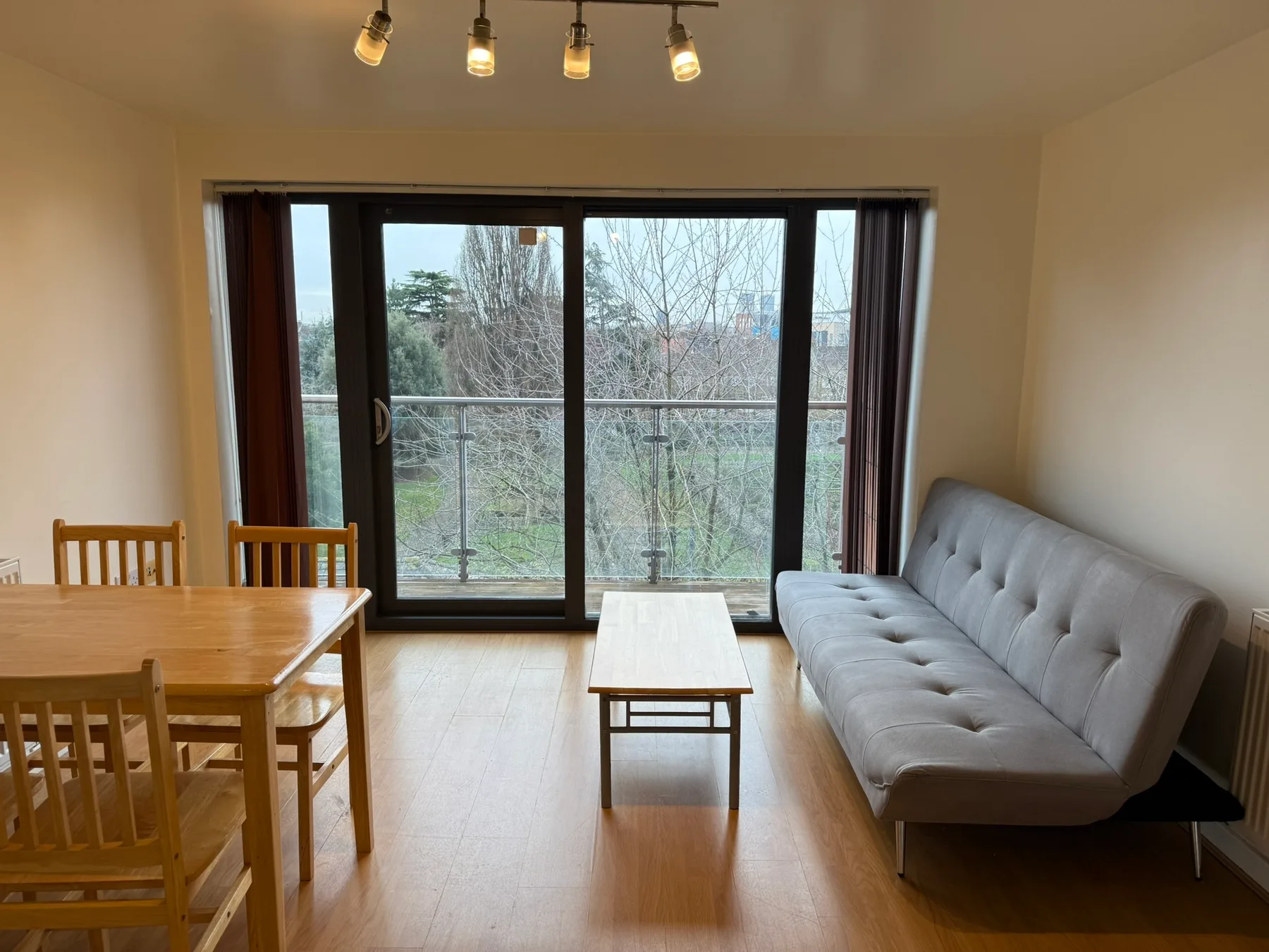 A living room with a dining table and seating beside a large window.