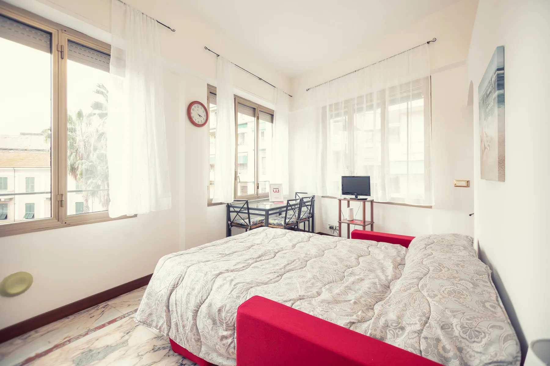 A bright bedroom with a large bed and tall windows.