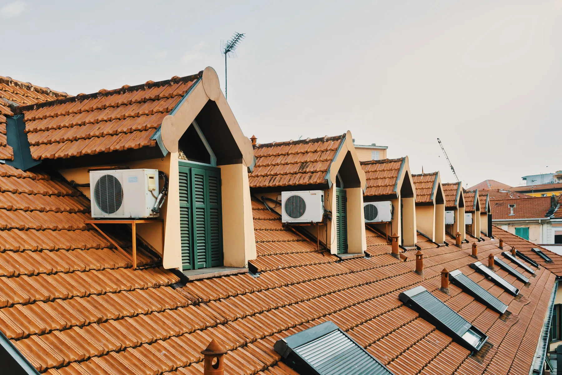 A row of dormer windows and skylights sits across a red-tiled roof.