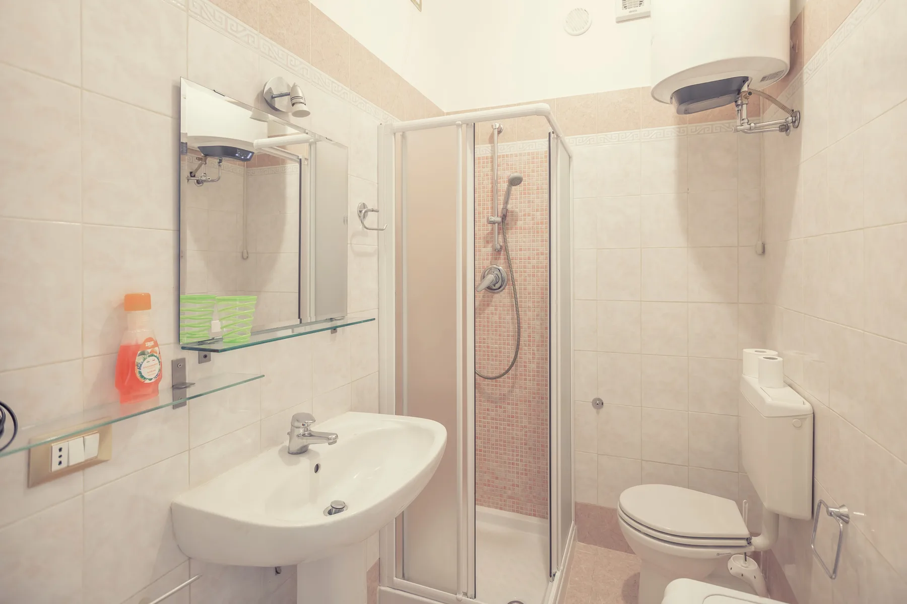 A tiled bathroom with a sink, mirror, and shower.