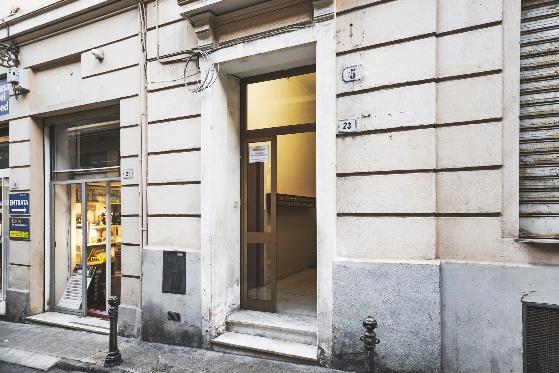A building entrance with an open glass door beside a street-facing shop window.