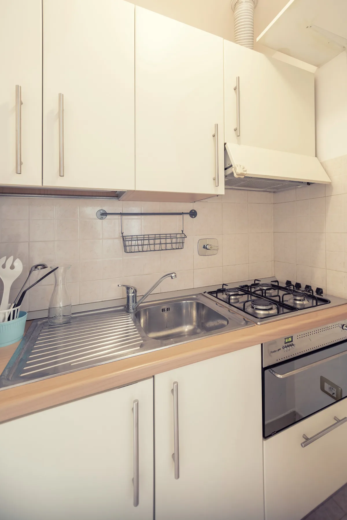 A kitchen with white cabinets, a sink, and a stovetop.