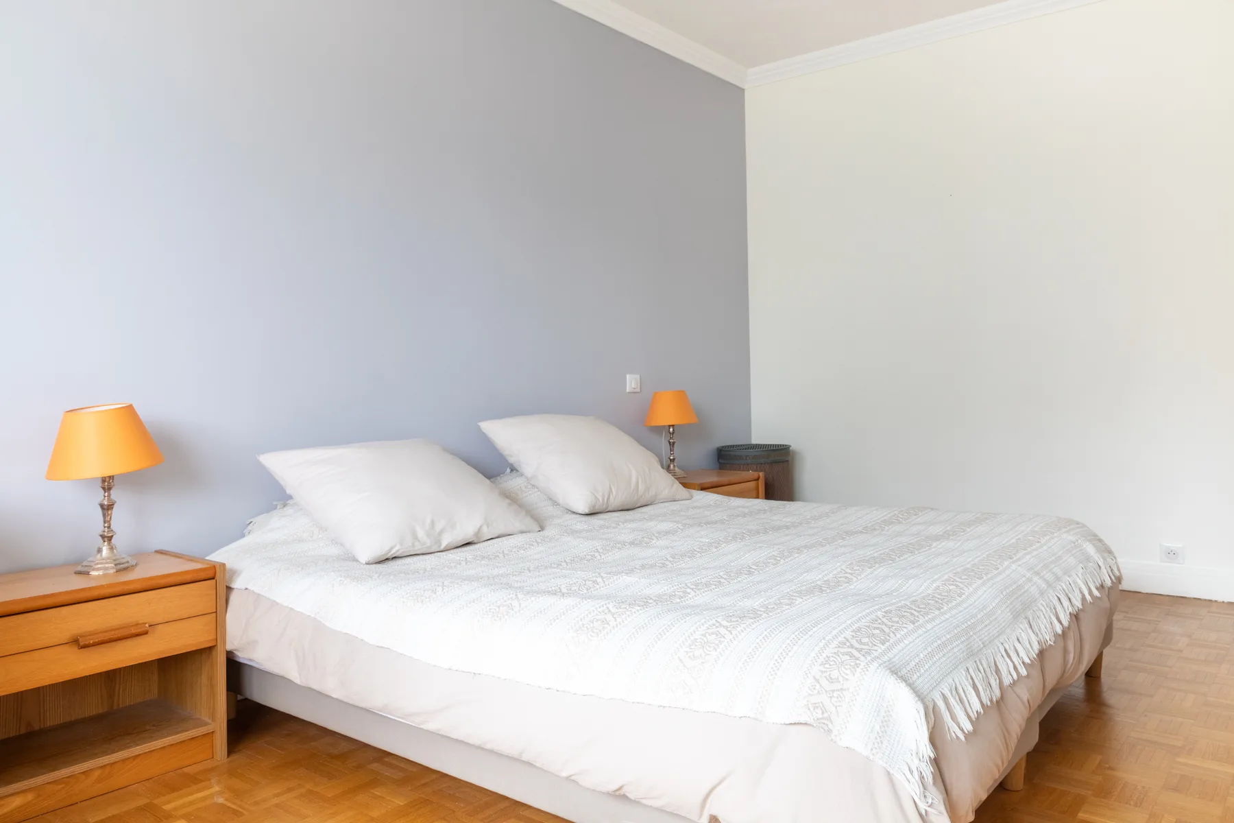 A bedroom with a neatly made bed and wooden bedside tables.