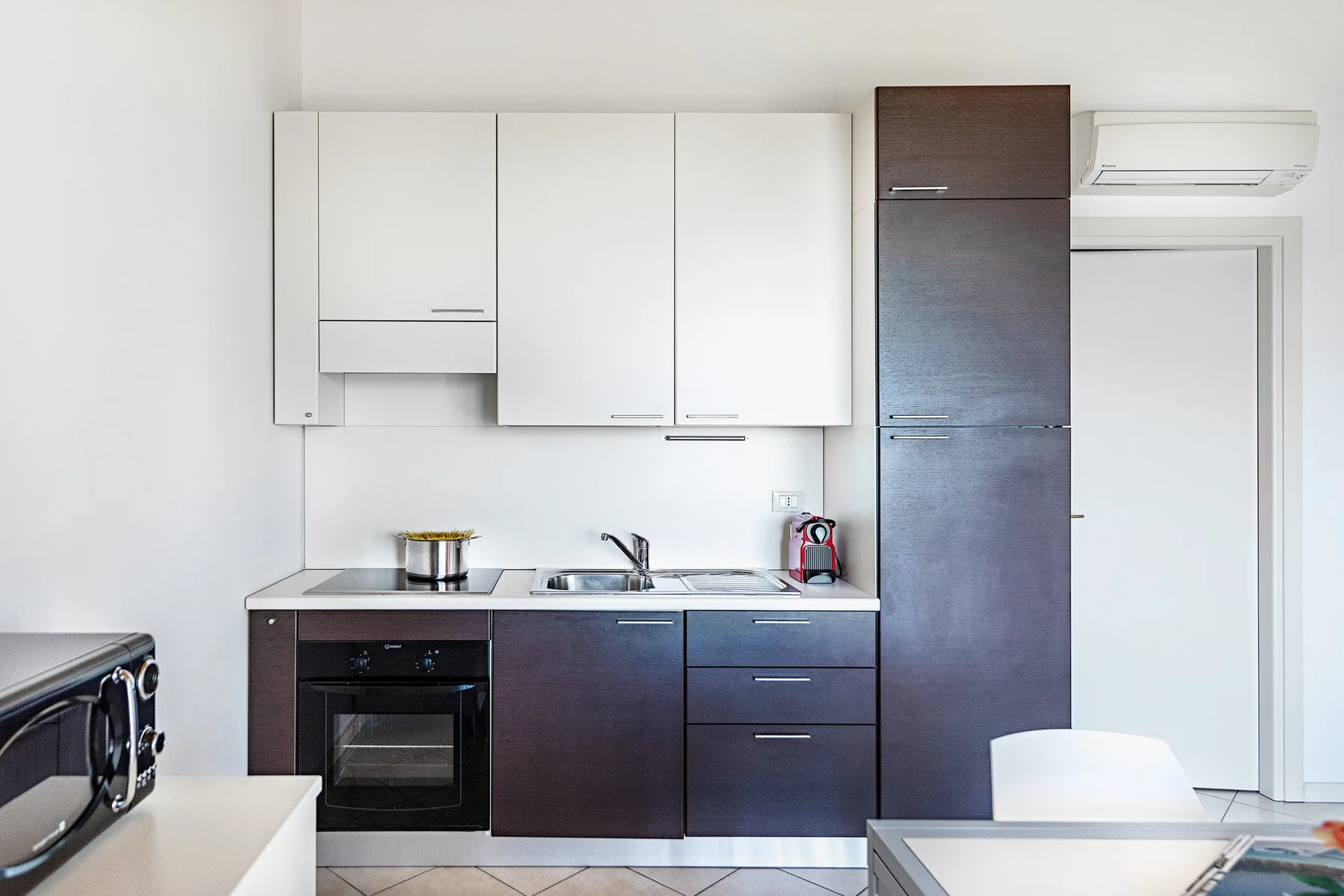A compact kitchen with dark lower cabinets and white upper cabinets.