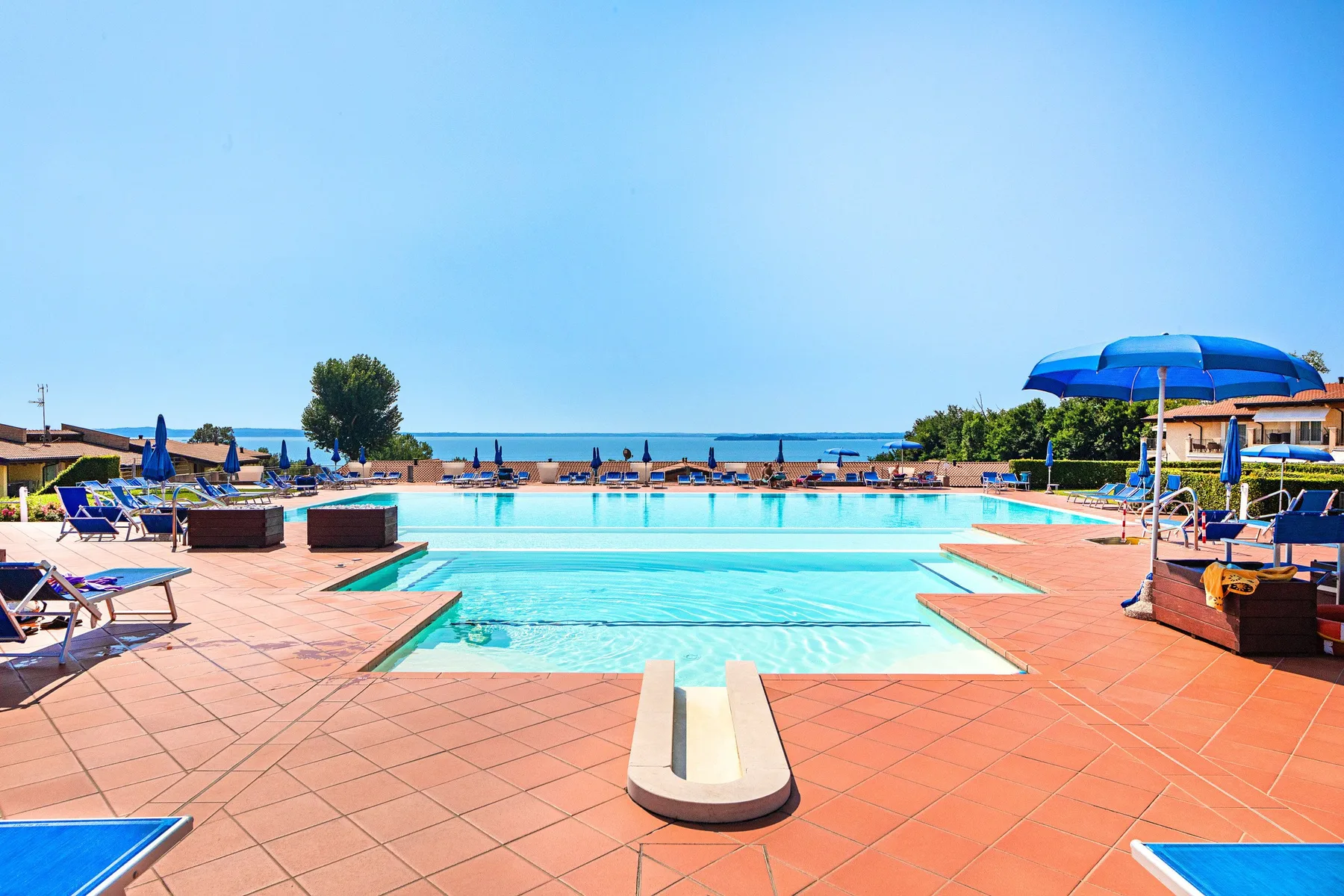 A swimming pool and surrounding tiled deck overlook the sea.