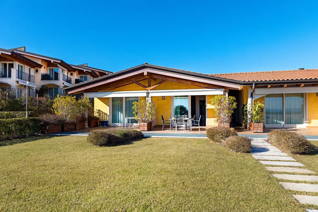 A single-story house with a covered patio opens onto a lawn and stepping-stone path.