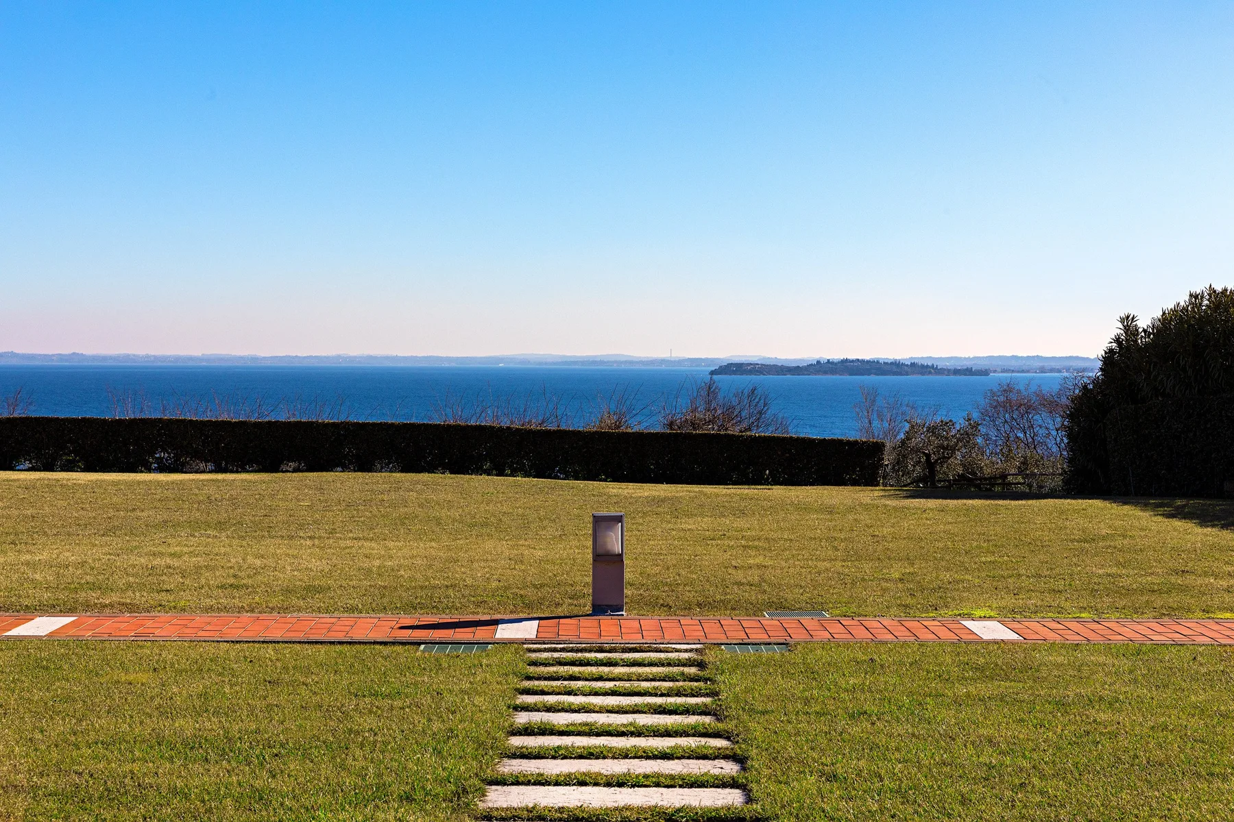 A grassy lawn with a stepping-stone path leads toward a view of the water.