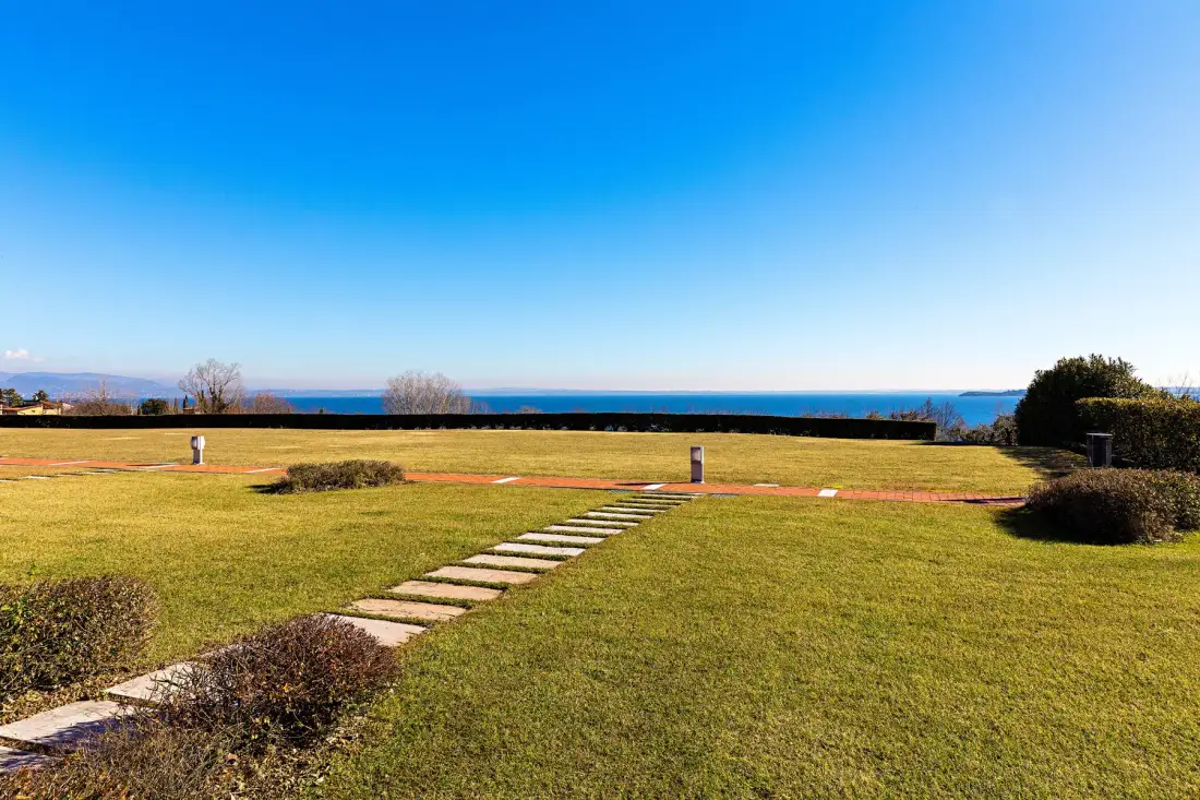 A grassy outdoor lawn with a stepping-stone path and ocean views.