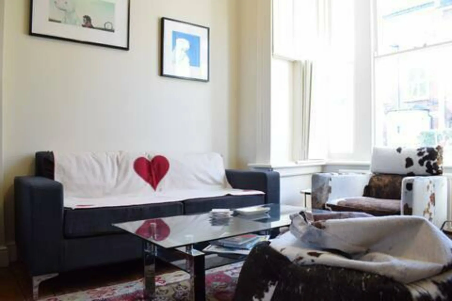 A living room with seating, a glass coffee table, and bright windows.