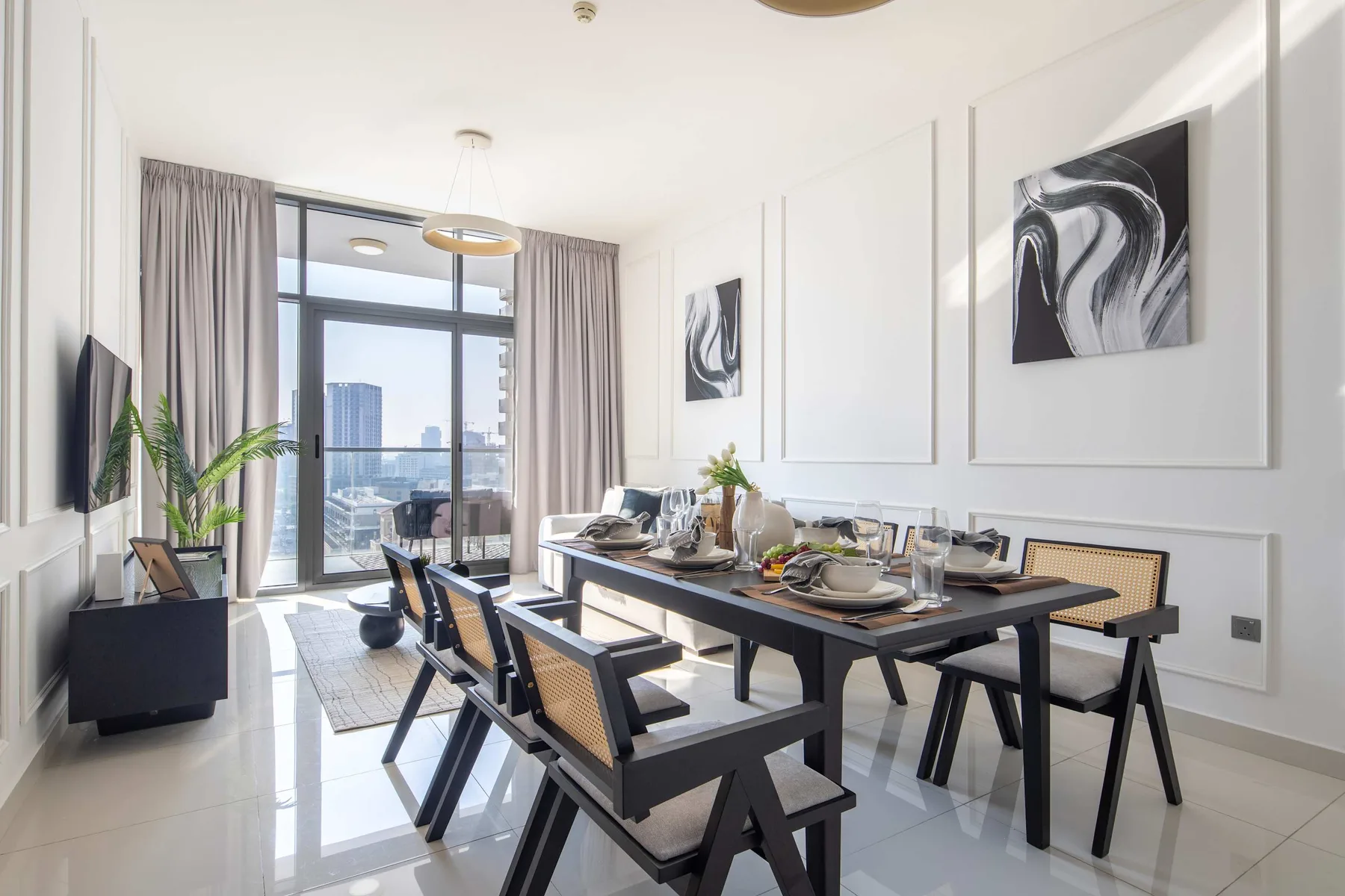 Un comedor luminoso con una mesa larga, asientos y grandes ventanales.