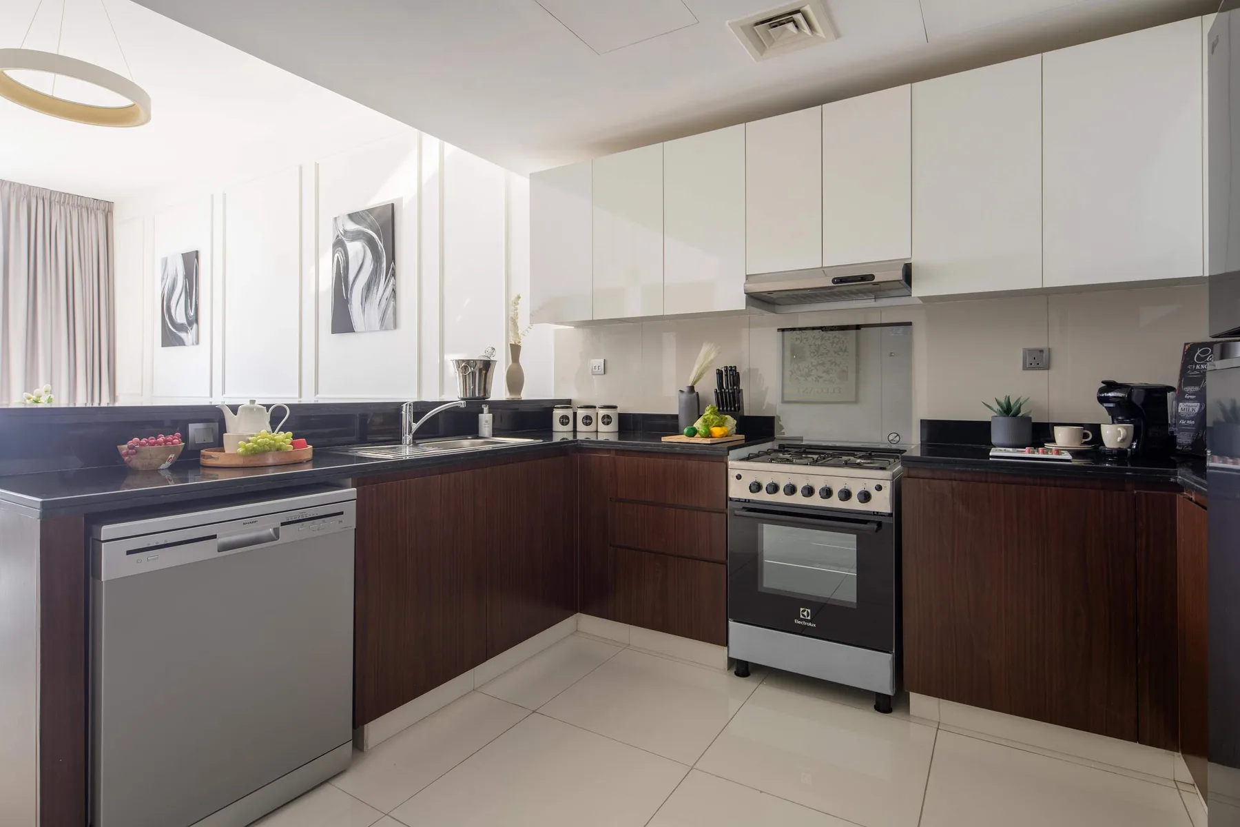 A modern kitchen with dark lower cabinets, light upper cabinets, and a stove.
