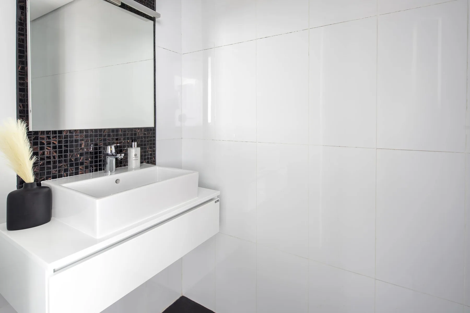 A bright bathroom with a white sink and a large wall mirror.