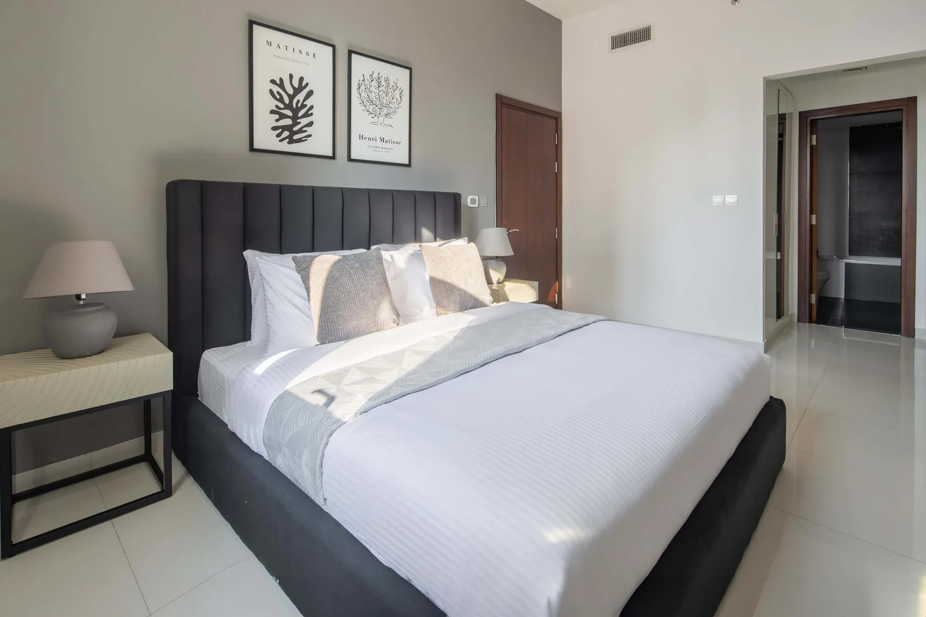 A bedroom with a neatly made bed and framed botanical prints above the headboard.