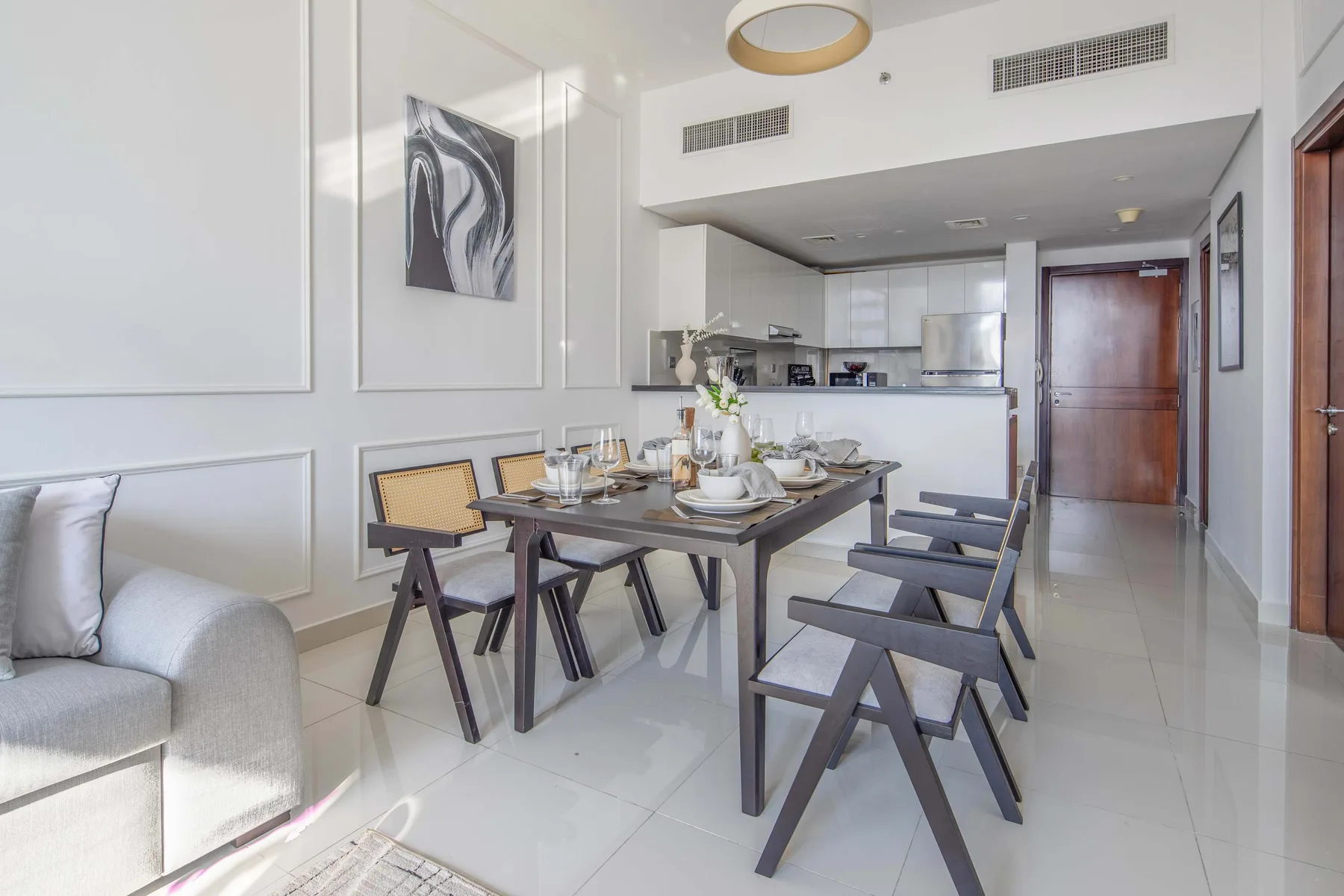 A bright dining area with a table set in front of an open kitchen.