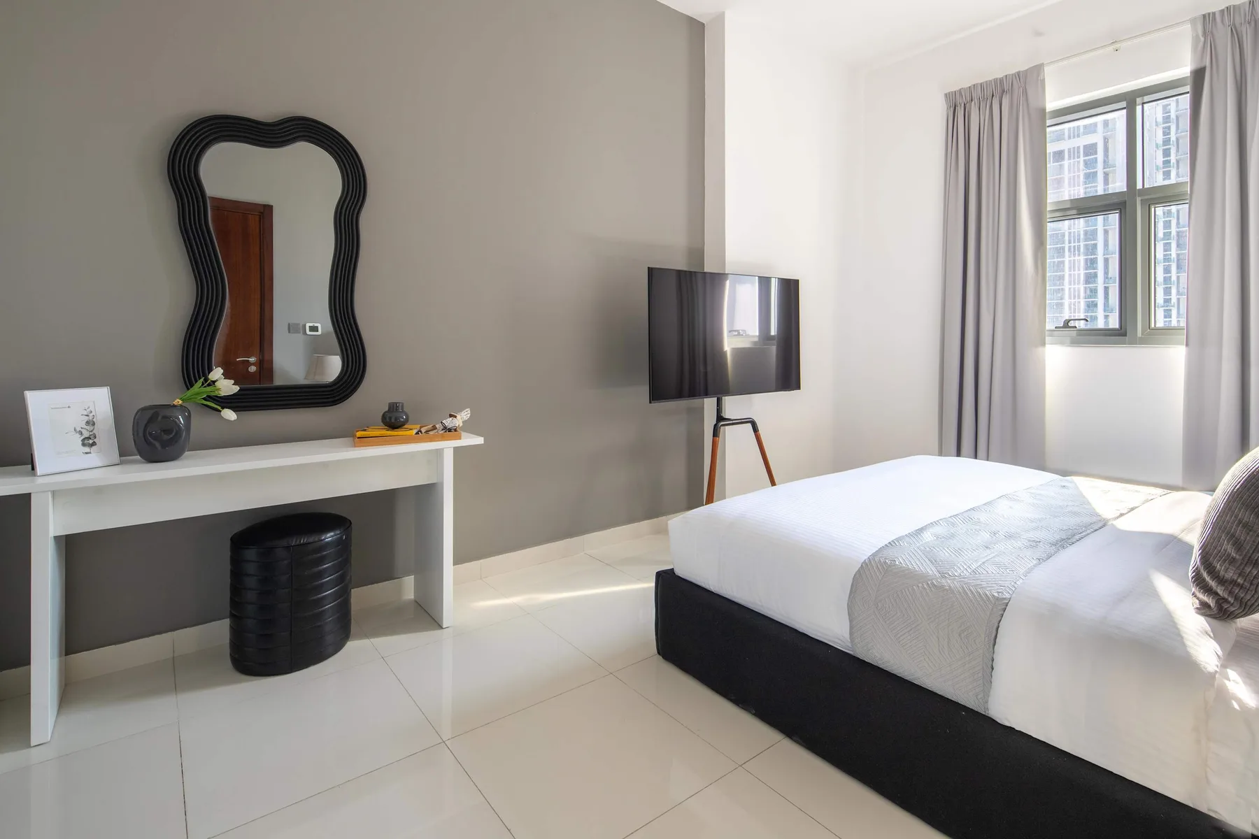 A bright bedroom with a bed, a console table, and a television.