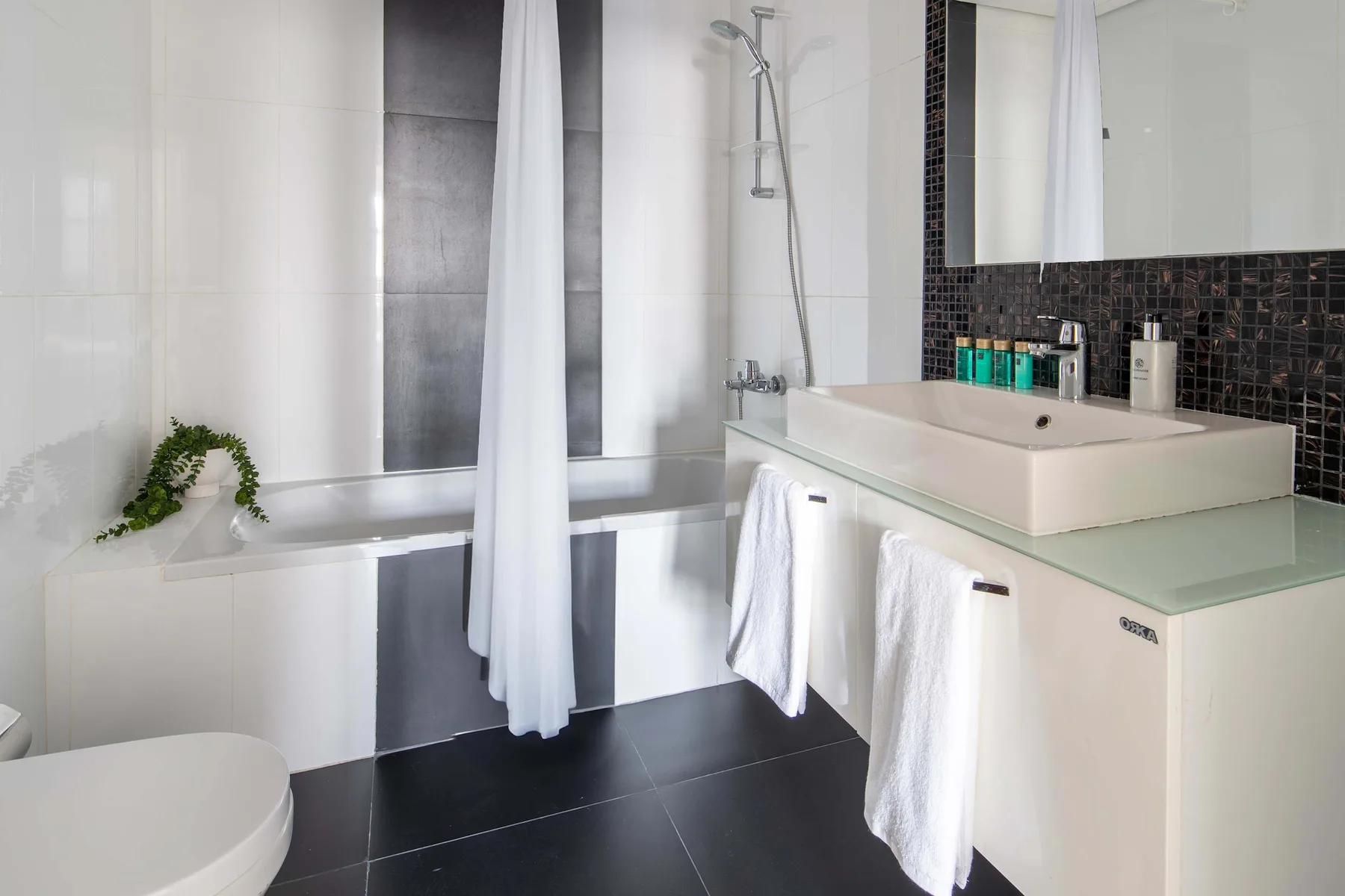 A tiled bathroom with a bathtub, shower, and vanity.