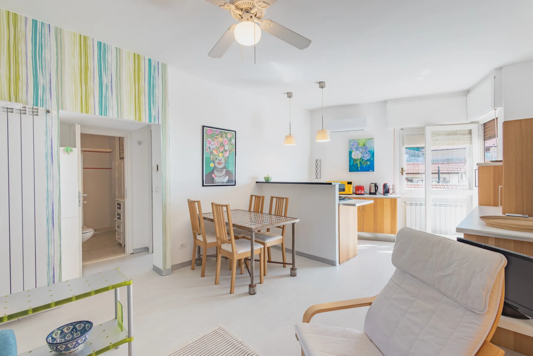 A bright open-plan dining and kitchen area with a table beside the kitchen counter.