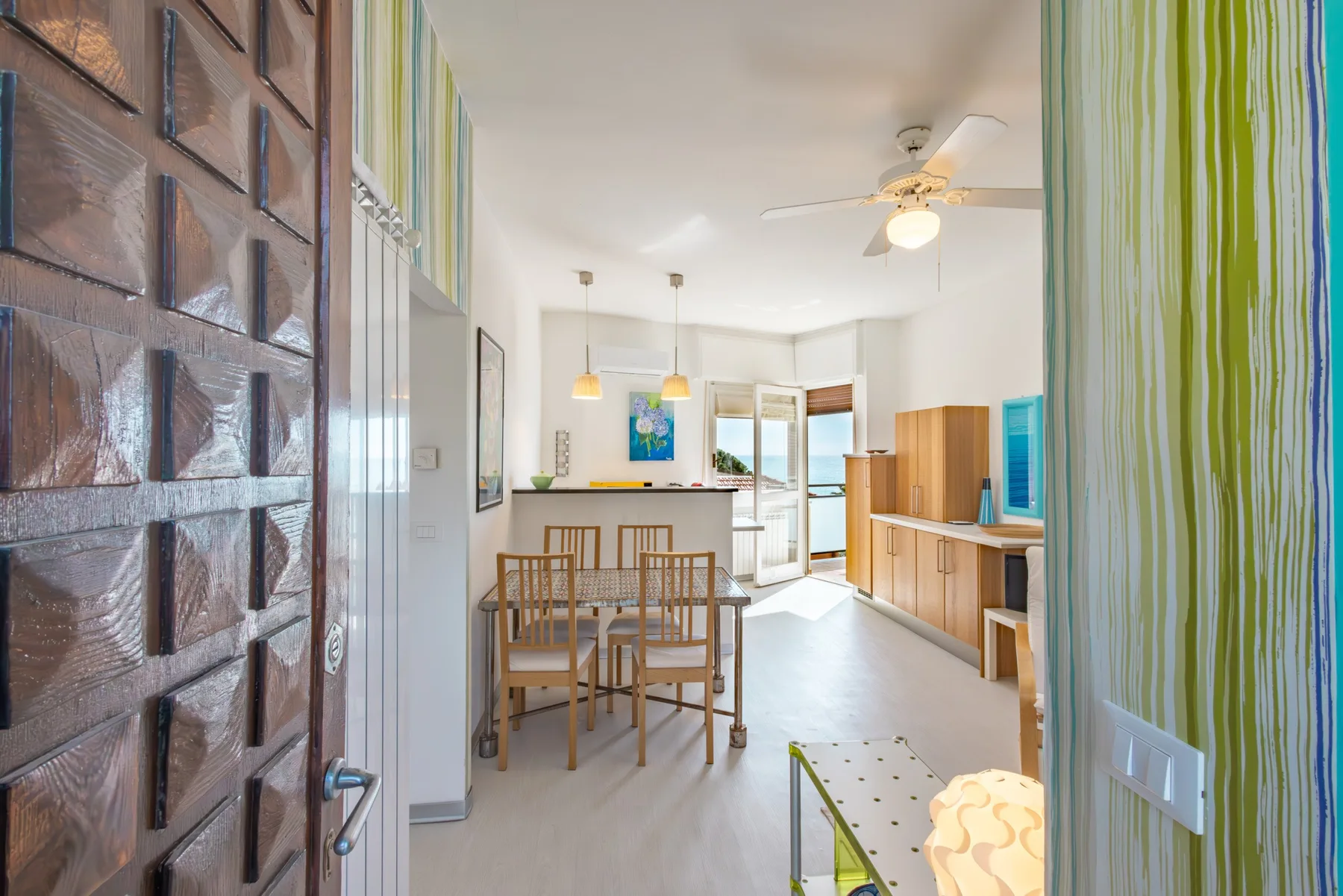 Una luminosa zona de comedor y cocina con una mesa de madera y asientos.