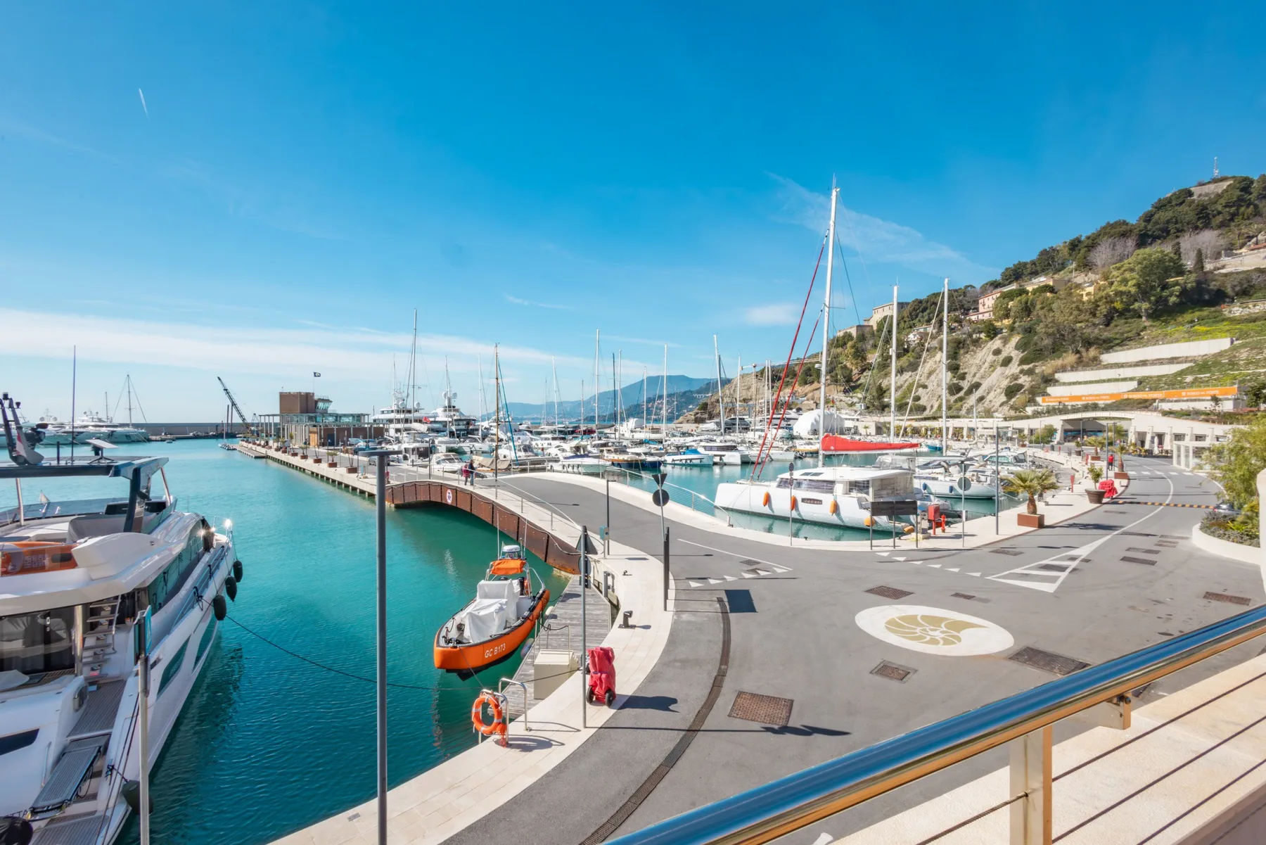 Un paseo del puerto deportivo bordea el agua turquesa, con barcos amarrados junto al muelle.