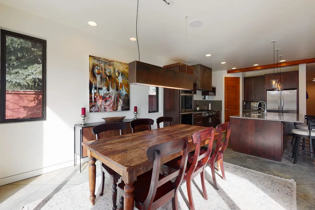 Cocina y comedor de concepto abierto con una mesa larga de madera e isla de cocina.
