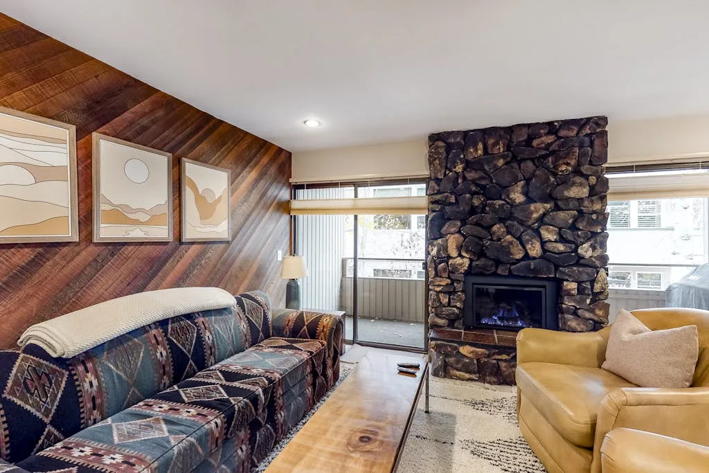 Una sala de estar con asientos estampados y una chimenea de piedra.