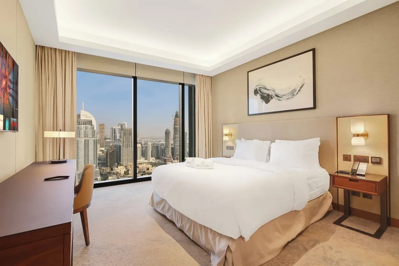 Un dormitorio con una cama grande junto a ventanales con vistas a la ciudad.