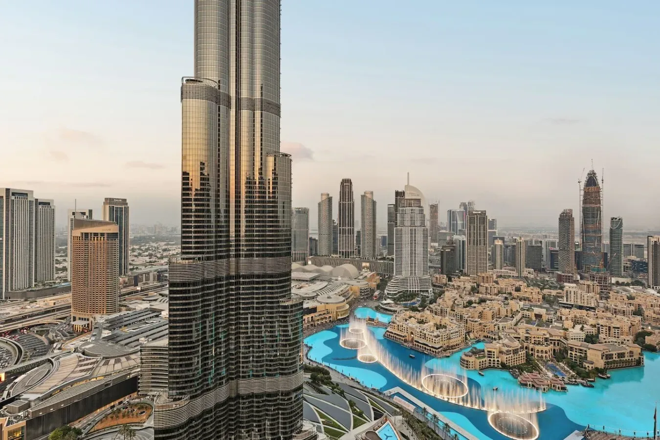 Un horizonte urbano domina una zona costera turquesa con fuentes y edificios alrededor.
