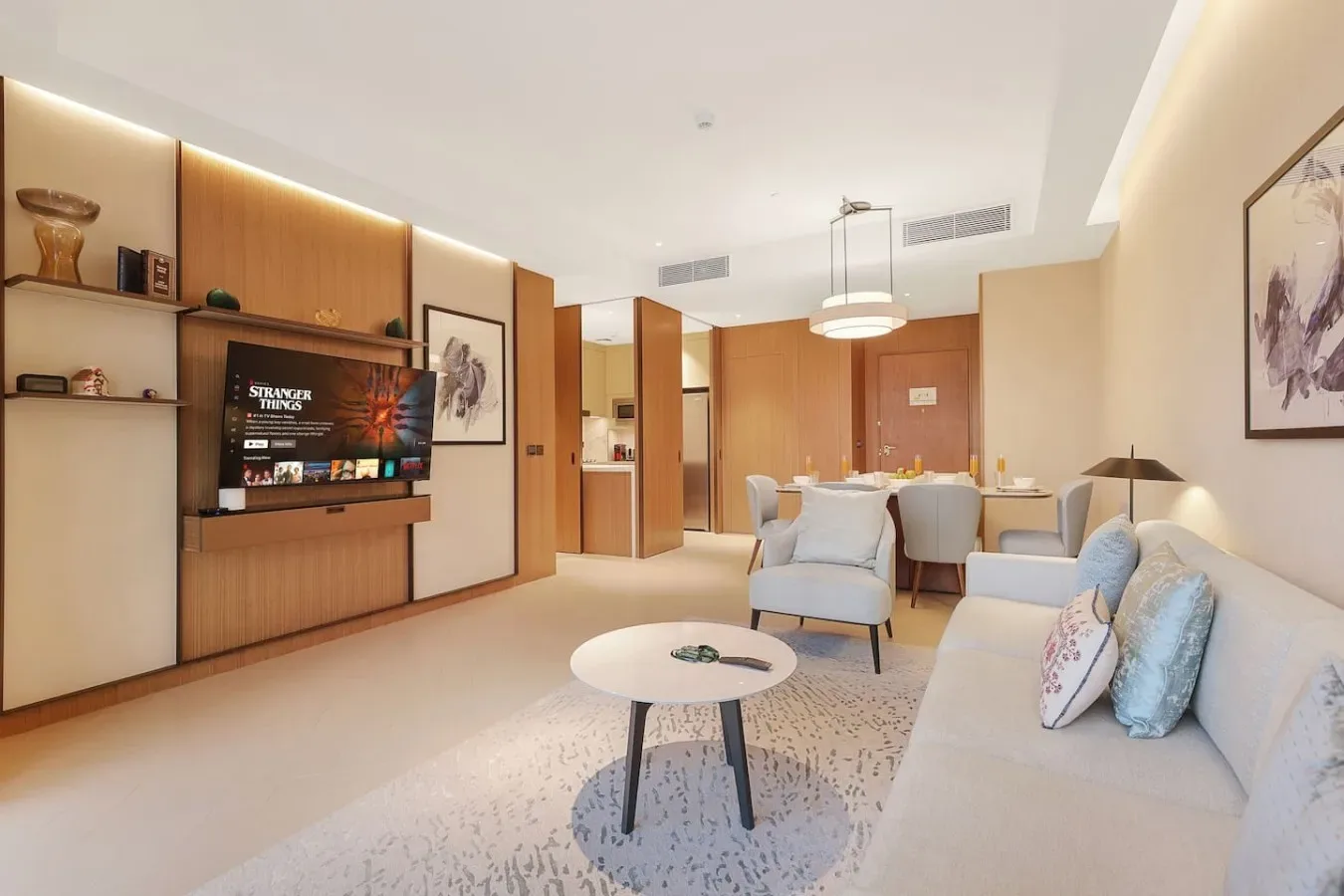 Una luminosa sala de estar con asientos, una mesa de centro y un televisor en la pared.