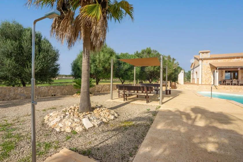 Un patio exterior con una zona de comedor a la sombra junto a una piscina.