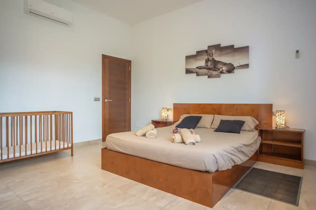 Un dormitorio con una cama de madera, mesitas de noche y una cuna.
