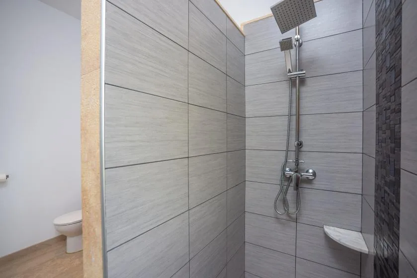 Una ducha de baño alicatada con un cabezal montado en la pared.