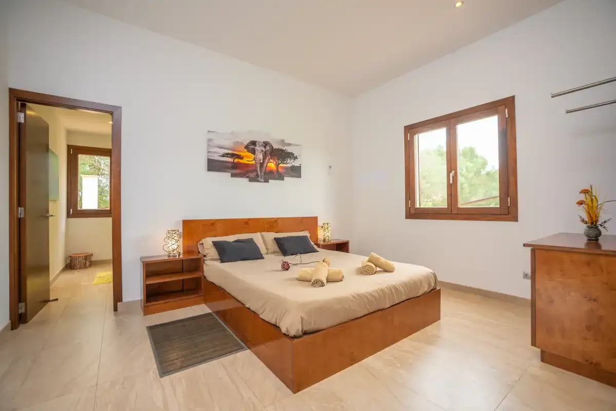 Un dormitorio con una cama doble, mesillas de noche y una ventana.