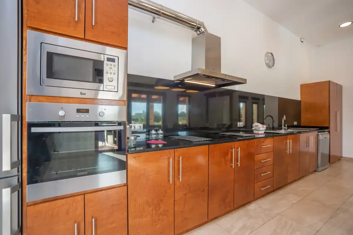 Una cocina moderna con gabinetes de madera, electrodomésticos integrados y una larga encimera.